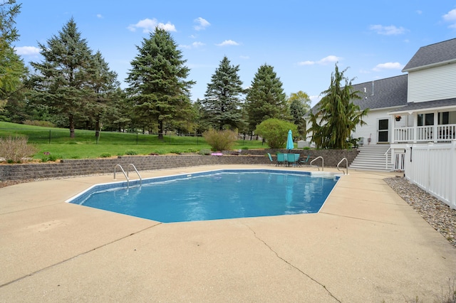 pool with stairs, a patio area, fence, and a yard
