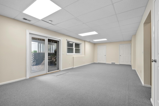 carpeted empty room with visible vents, a paneled ceiling, and baseboards