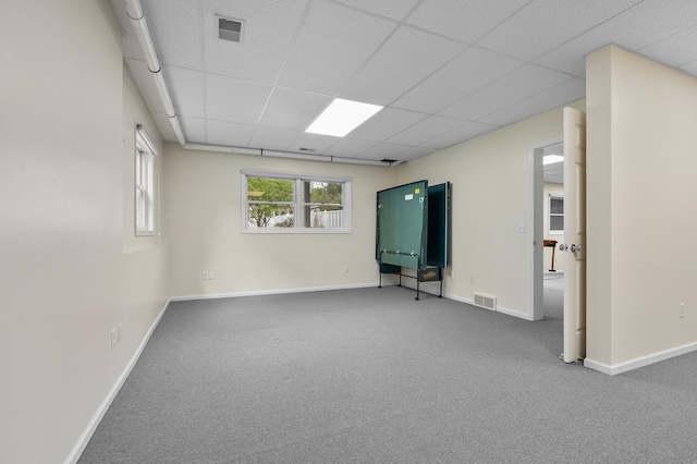 carpeted spare room featuring visible vents, a paneled ceiling, and baseboards