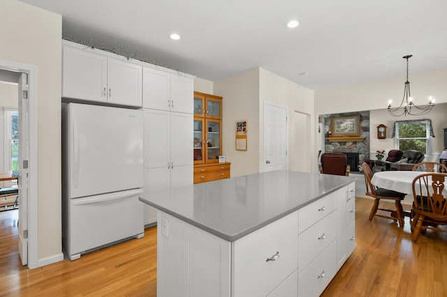 kitchen with light wood-style floors, freestanding refrigerator, and white cabinets