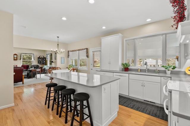 kitchen with a breakfast bar, a sink, white appliances, a chandelier, and a center island