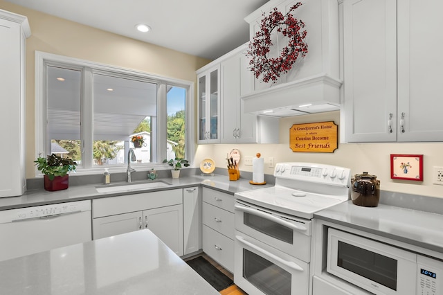 kitchen with a sink, glass insert cabinets, white appliances, and light countertops