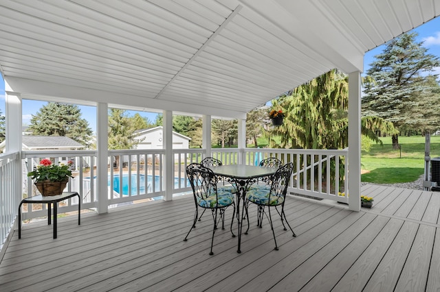 wooden deck with an outdoor structure, a lawn, outdoor dining area, and an outdoor pool