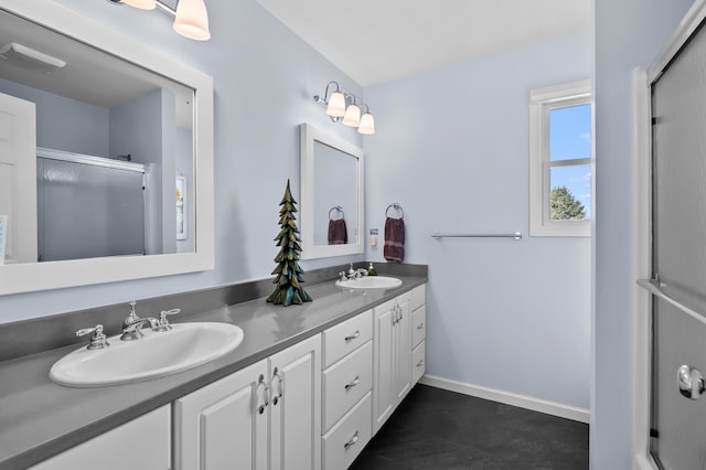 bathroom with double vanity, baseboards, a sink, and a stall shower