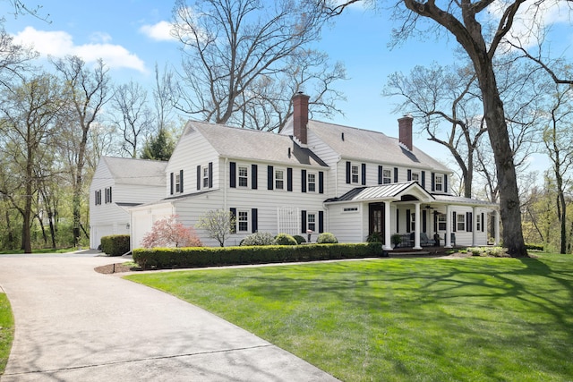 view of front of house featuring a garage, a front yard, a chimney, concrete driveway, and a porch