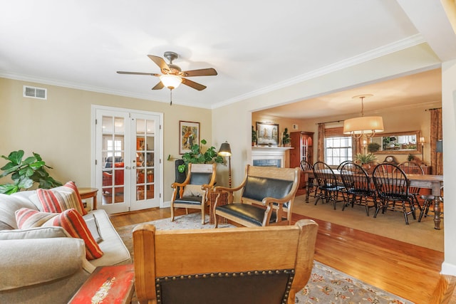 living area featuring ceiling fan, french doors, wood finished floors, visible vents, and ornamental molding