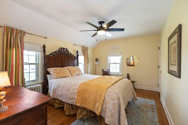 bedroom featuring baseboards, multiple windows, wood finished floors, and radiator