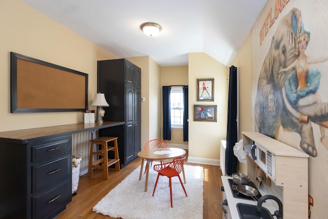 dining space featuring baseboards, vaulted ceiling, and light wood-style floors