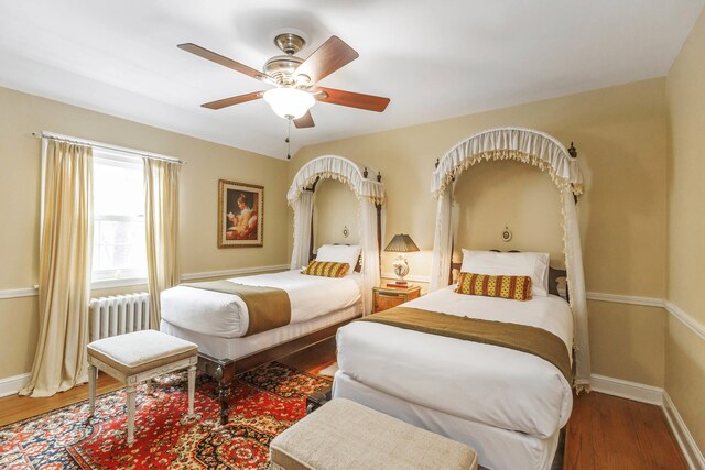 bedroom with baseboards, ceiling fan, radiator heating unit, and wood finished floors