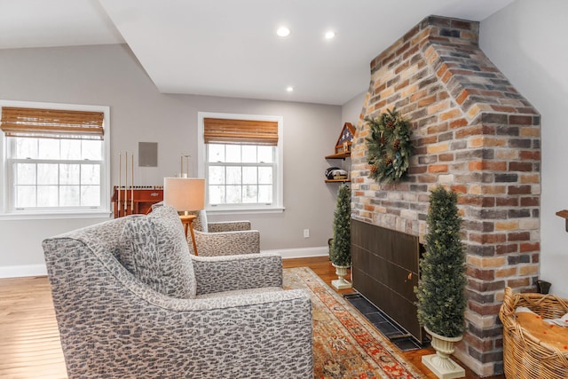living area featuring baseboards, recessed lighting, wood finished floors, and a fireplace