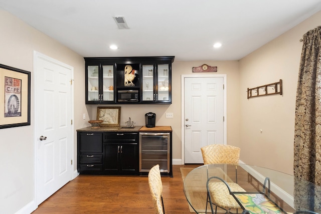 bar featuring visible vents, wine cooler, indoor wet bar, recessed lighting, and dark wood finished floors