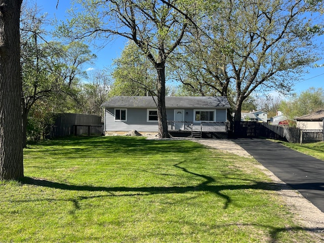 back of house featuring a lawn, a wooden deck, driveway, and fence