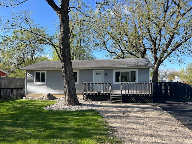 ranch-style home with a deck, fence, and a front lawn