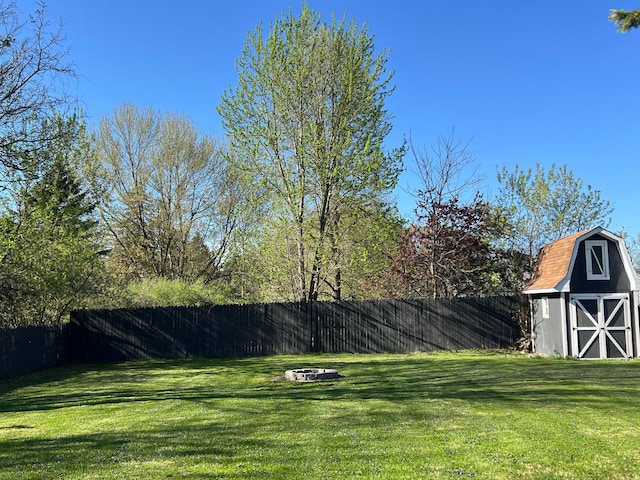 view of yard featuring a barn, an outbuilding, a fenced backyard, and an outdoor fire pit