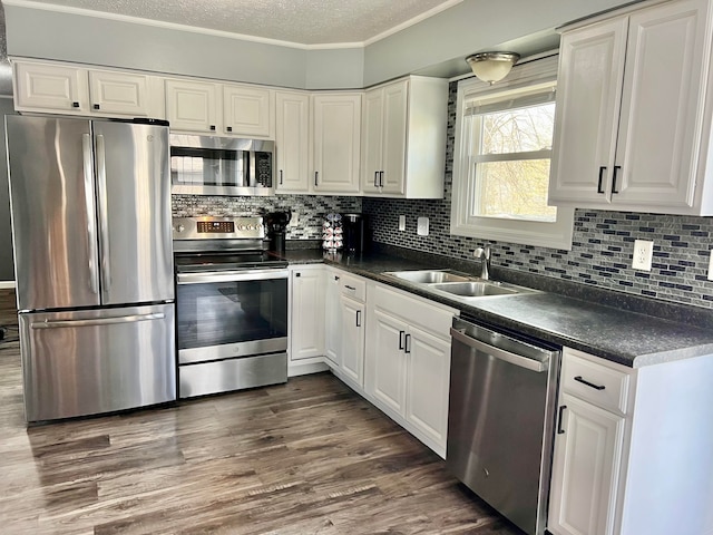 kitchen featuring a sink, white cabinetry, dark countertops, and stainless steel appliances