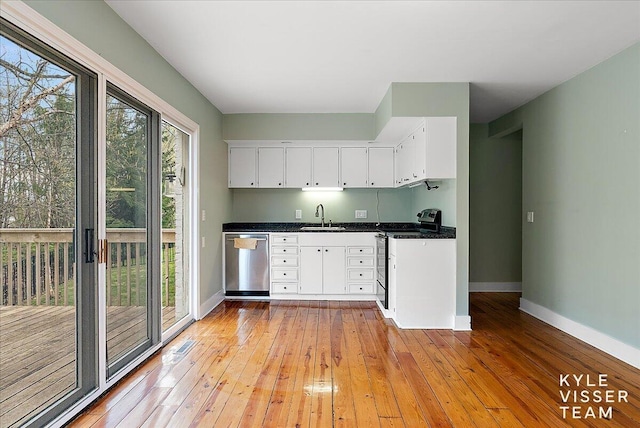 2630 Reeds Lake Ct SE, Grand Rapids, MI 49506 - kitchen with stainless steel dishwasher, range with gas stovetop, baseboards, a sink, and dark countertops