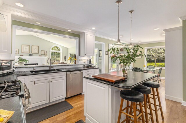 kitchen with dark countertops, appliances with stainless steel finishes, a sink, and a kitchen bar