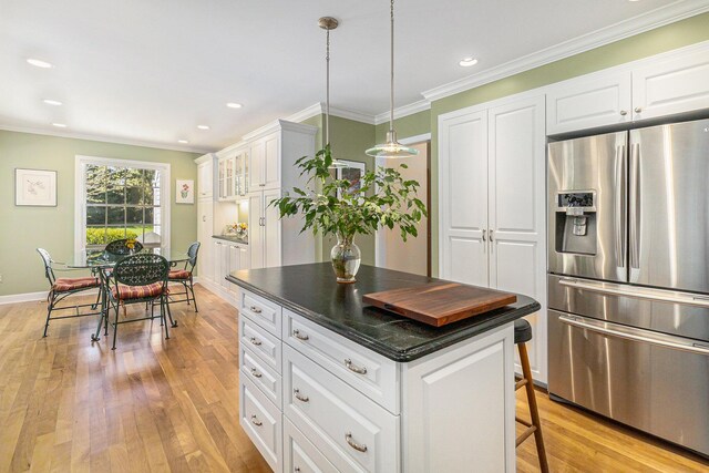 kitchen with dark countertops, light wood-style floors, a center island, stainless steel refrigerator with ice dispenser, and ornamental molding