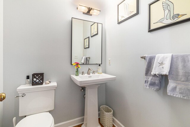 bathroom featuring toilet, baseboards, and a sink