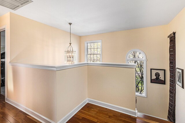 hallway with baseboards, dark wood-style floors, an upstairs landing, and an inviting chandelier