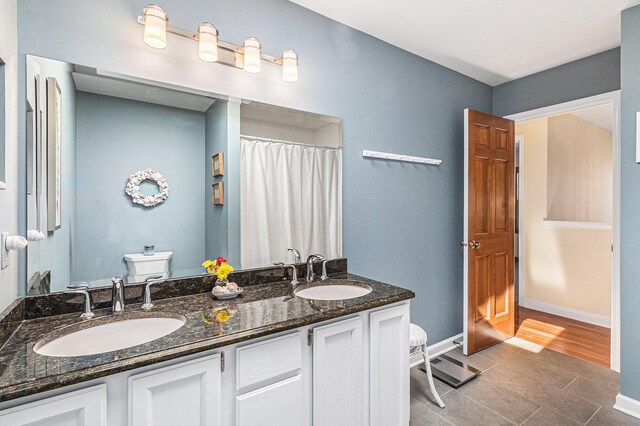 full bath featuring double vanity, toilet, baseboards, and a sink