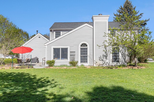 back of house with a lawn, a patio, and a chimney