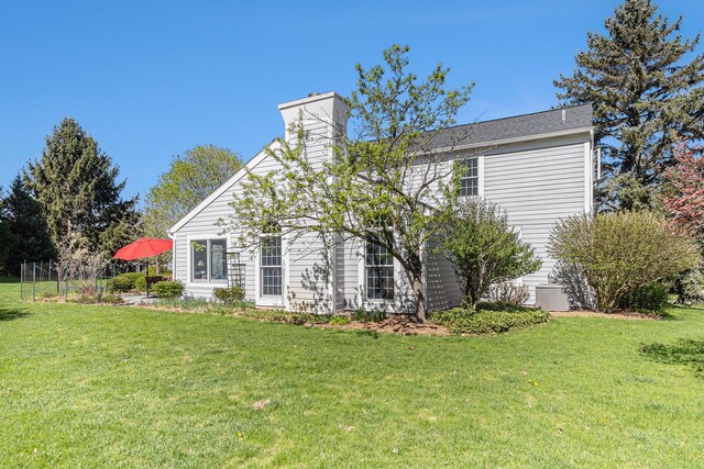 back of property featuring a lawn and a chimney