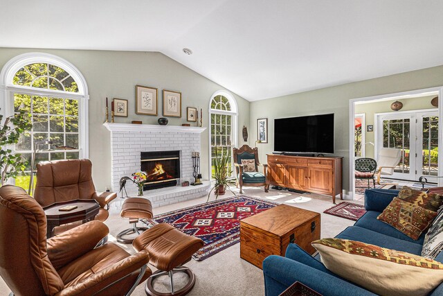 carpeted living room featuring a brick fireplace, vaulted ceiling, and plenty of natural light