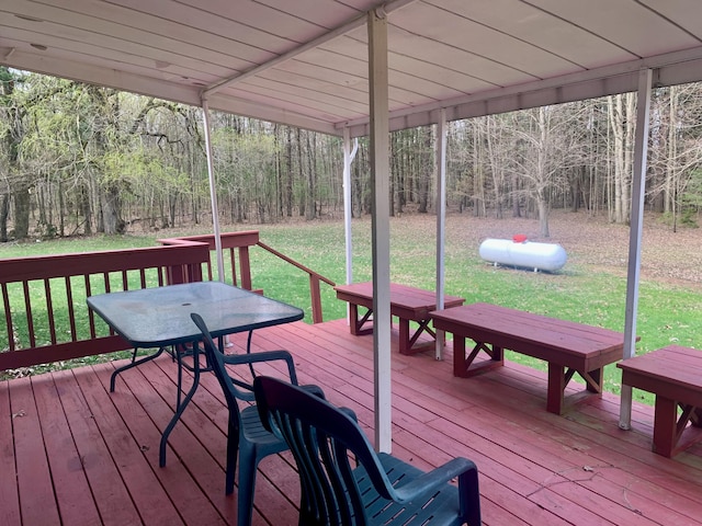 deck featuring outdoor dining area, a yard, and a forest view
