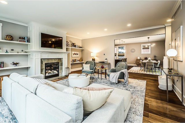 living area featuring dark wood finished floors, recessed lighting, baseboards, a tile fireplace, and ornamental molding