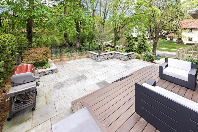 wooden deck with a patio, fence, and a grill