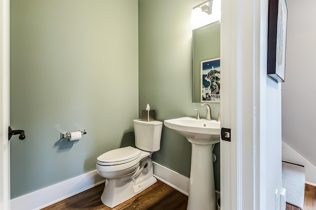 bathroom featuring toilet, baseboards, a sink, and wood finished floors