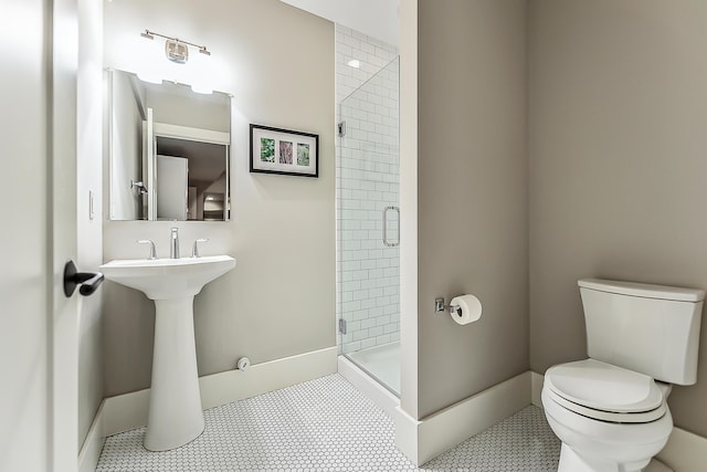 bathroom with baseboards, tile patterned flooring, a stall shower, and toilet