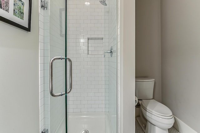 bathroom featuring baseboards, toilet, and a shower stall