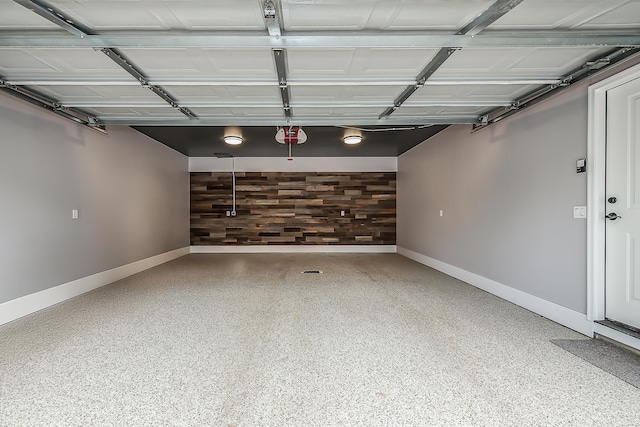 garage featuring baseboards, a garage door opener, and wood walls
