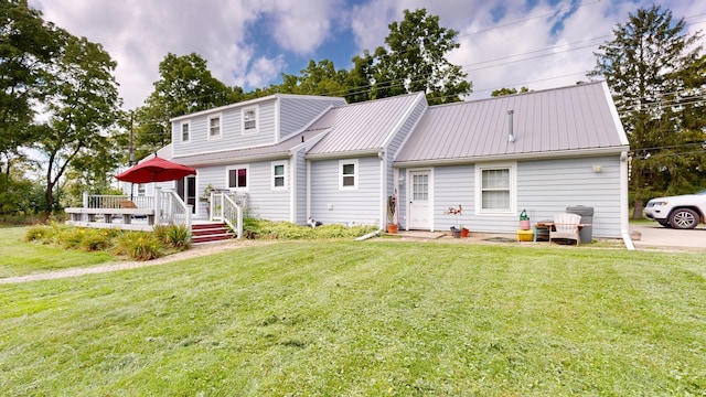 back of property featuring a lawn, metal roof, and a deck