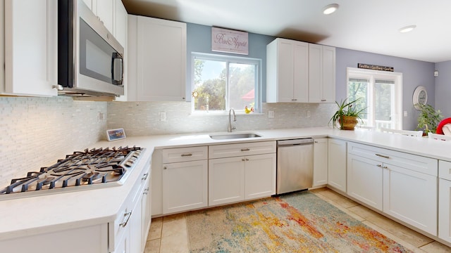 kitchen featuring light countertops, stainless steel appliances, white cabinetry, and a sink