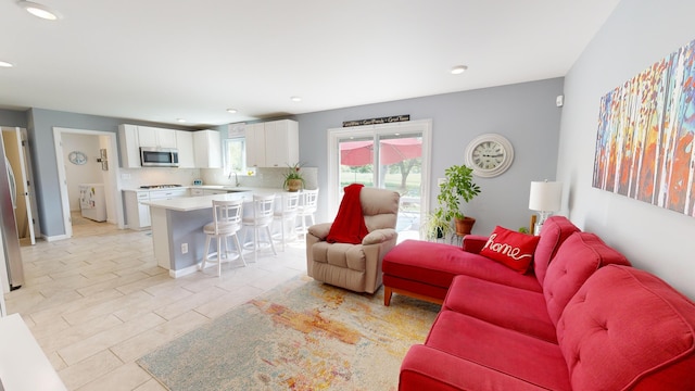 living area featuring washer / clothes dryer, recessed lighting, baseboards, and light tile patterned floors