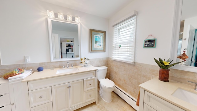 bathroom featuring tile walls, a wainscoted wall, a baseboard radiator, vanity, and toilet