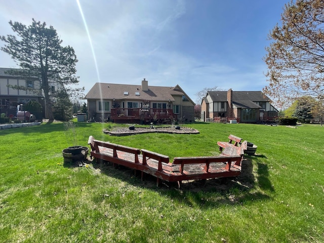 rear view of house featuring a chimney, a yard, and a deck