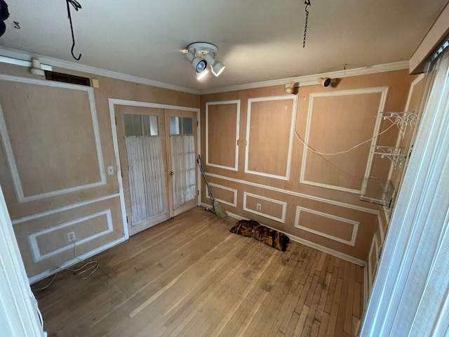 spare room with wood-type flooring, ornamental molding, french doors, and a decorative wall
