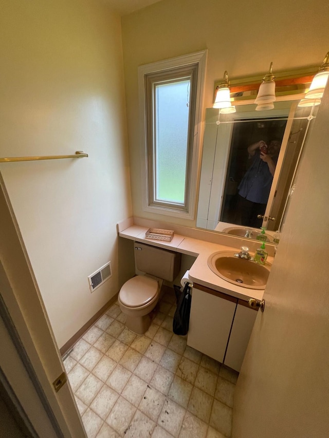 half bathroom featuring vanity, baseboards, toilet, and visible vents