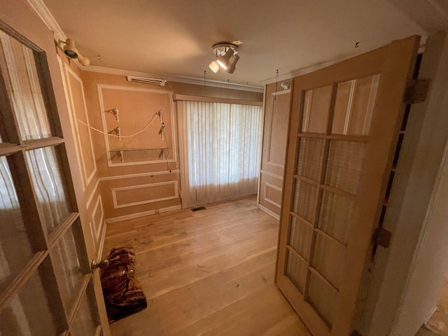 interior space with crown molding, visible vents, and light wood-style flooring