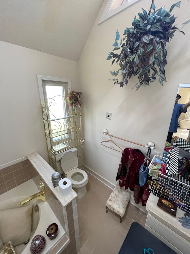 full bathroom with tile patterned floors, a bathtub, vaulted ceiling, and toilet