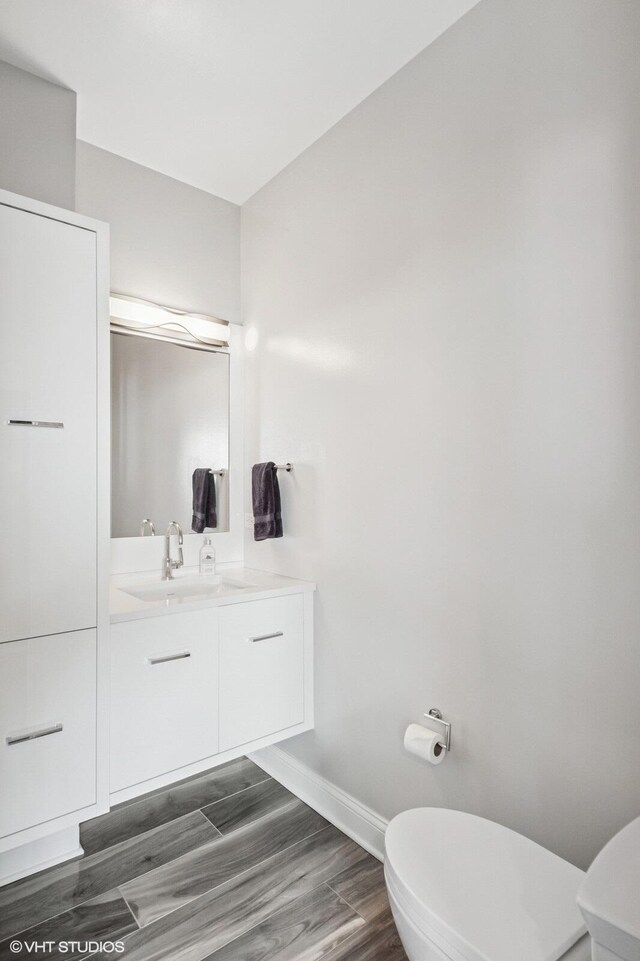 bathroom featuring vanity, baseboards, toilet, and wood finished floors