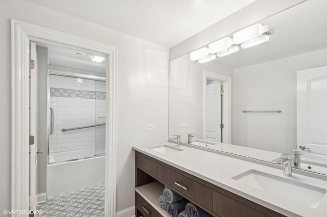 bathroom with double vanity, a sink, and bath / shower combo with glass door