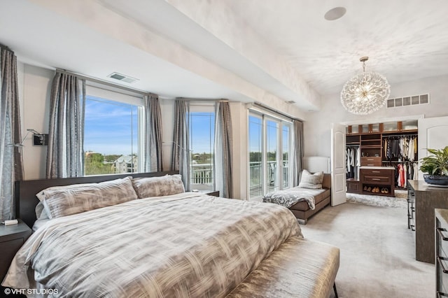 bedroom featuring visible vents, a walk in closet, a notable chandelier, and light carpet