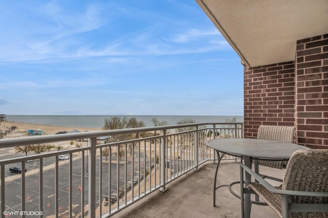 balcony featuring a view of the beach and a water view