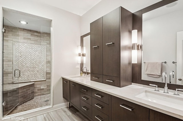 bathroom featuring double vanity, a sink, baseboards, and a stall shower