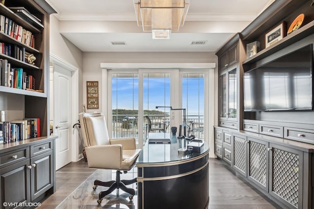office area with crown molding, visible vents, and wood finished floors